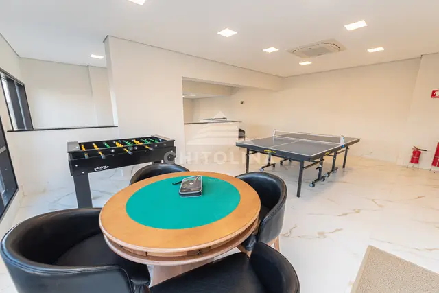 Mesa de carteado com poltronas, pebolim e pingue-pongue no salão de jogos do Edifício Cathedral.