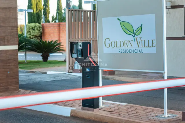 Cancela e totem de identificação ao lado da placa com o logotipo do residencial.