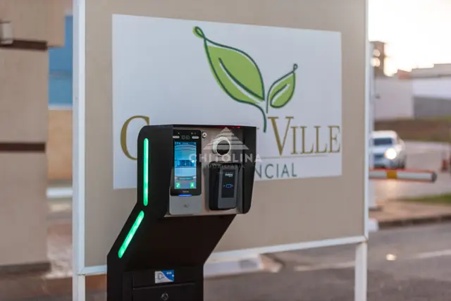 Leitor com tela de reconhecimento facial e biometria diante da placa Golden Ville.