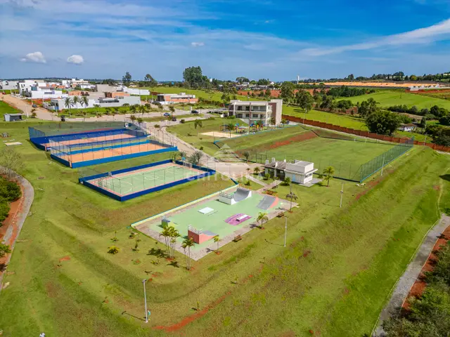 Vista aérea da área de lazer com quadras de tênis, quadra poliesportiva, pista de skate e campo.